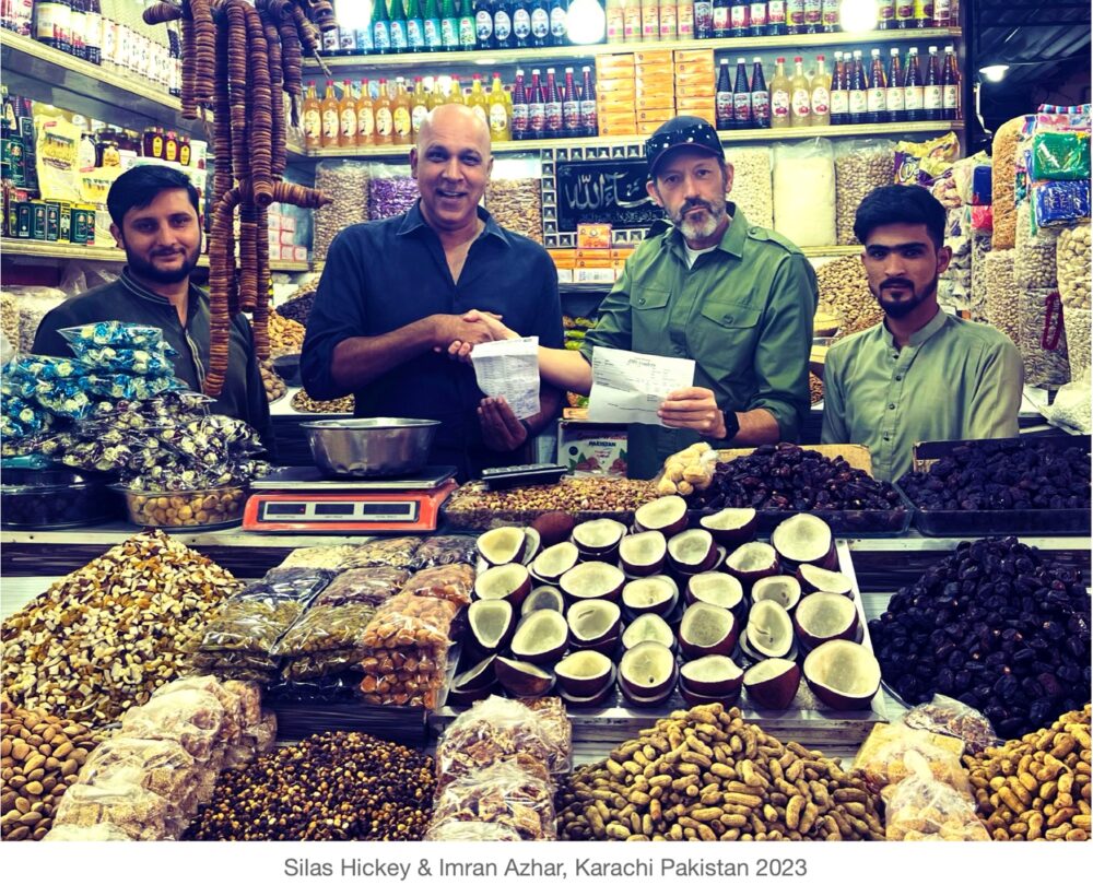 A group of men standing in a market Description automatically generated